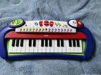Top view of the Fisher Price kids piano showing the 25 piano keys, various control buttons, speakers, and color scheme.