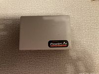 Closed gray rectangular device case with PowerLine logo on top.