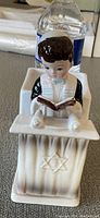 Front view of ceramic figurine of boy reading Torah scroll on podium with Star of David