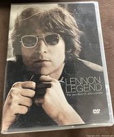 Front cover of the DVD showing a close-up black and white photo of John Lennon wearing sunglasses and holding his glasses.