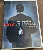 Front cover of the DVD case showing Paul McCartney's back with thumb painted as an American flag with the title 'back in the u.s. concert film'.