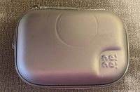 Closed grey hard shell case with embossed NoNo logo on top, smooth finish.