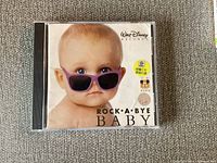 Front cover of Rock a Bye Baby CD by Walt Disney Records featuring a baby with purple sunglasses.