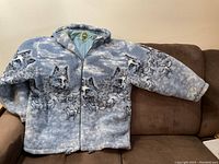 Front view of the winter women's coat with wolf and forest design, showing texture and zipper.