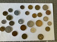 Top view of various world coins arranged on white graph paper showing front sides.