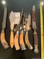 Full view of all six utensils with bone and antler handles showing metal decorative ends and overall wear.