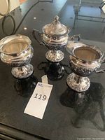 Lot of three silver plate vessels displayed on black surface with auction lot number 119 visible.