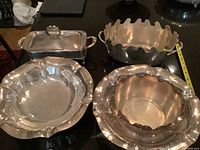 View of four silver plated serving items: three bowls and one rectangular covered dish, showing overall size and shape