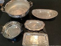 Lot overview showing all five silver plate serving pieces on a black surface.
