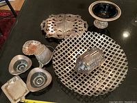 Photo showing the full lot including the large lattice basket, piggy bank shaped like a beetle, trivet, piggy bank, small jug, tiny tray, two matching bowls, and clamshell dish on a dark surface.
