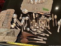 Overview of lot showing knives in roll, loose spoons, ladles, spreaders and servers