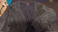 Black and silver sparkly shrug shown, knit material with shimmer and subtle sequin details
