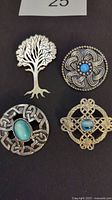 Four Celtic design brooches on black background showing entire set.