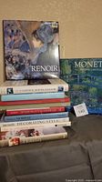 Photo showing stacked books including Renoir art book on top, Monet book, and several home, garden, decorating and entertaining titles below.