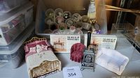 Full view of bed, chair, stove, and millinery kits with The House of Miniatures brochures in background.