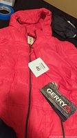 Bright pink ladies down and feather blend packable jacket with hood, tags attached showing size medium and Gerry brand.