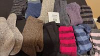 Photo of eleven pairs of wool socks in size 6/7 featuring various colors and stripe or solid patterns