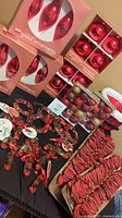 Photo showing the boxed red glass ornaments, shatterproof ornaments, Santa basket, resin ornaments, and the wired bows arranged on a table.