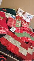Lot spread showing red and green Christmas fleece throws, multiple packs of red napkins, and wrapped tablecloths.