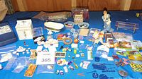 Overview photo showing various miniature accessories including sink, tub, tea set, paintings, and figurines on a blue cloth backdrop.