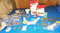 Photo showing the assortment of miniature Christmas gifts, candelabra, small decorative items and flatware spread on a blue cloth.