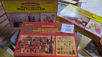 Photo of three boxed Realife Miniatures kits - two yellow and red boxes for furniture kits and one longer red box for country store accessories.