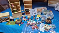 Full overview of miniature playroom and nursery items on blue fabric surface showing various furniture pieces, toys, and small accessories.