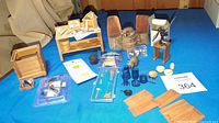 Wide view of miniature workbench, chairs, barrel, animal figurines, kitchenware, and accessories on blue felt.