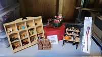 Wide view showing cubby shelf with miniatures, Santa sleigh, wooden hutch with Halloween decor, and resin dollhouse cabin