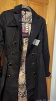 Front view of the black trench coat with button details and leopard print lining visible through front opening.
