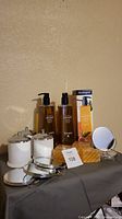 Shows all items in lot including three Neutrogena liquid soap bottles, eight soap bars, three white ceramic canisters and five small round stand mirrors.