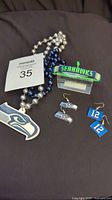 Photo shows two bead necklaces with Seattle Seahawks pendants, two pairs of Seahawks-themed earrings, and one woven Seahawks bracelet.
