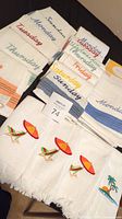 All days of the week kitchen towel sets arranged with four beach themed fingertip towels in front