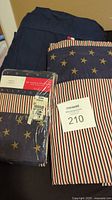 Photo showing folded patriotic striped top sheet and matching pillowcases in packaging along with folded navy blue fitted sheet