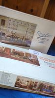 Photo showing unopened kit box for Queen Anne Collection miniature dining room furniture, with image on box of a detailed miniature dining room setup.