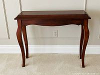 Front view of the darkwood console table showing its curved legs and rectangular top.