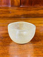Front view of the clear bubble-filled glass bowl on wooden surface.