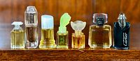 Front view of seven small perfume bottles on wooden shelf