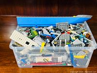 Large plastic bin filled with assorted LEGO bricks and pieces in various colors and shapes.