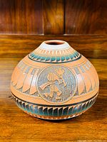 Front angle of the pottery vase showing round shape and Kokopelli design with surrounding geometric patterns in turquoise and brown.