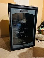 Full view of black Sanyo wine fridge with closed glass door and metal handle on the left.