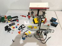 Top view of the entire Playmobil Esso gas station set showing canopy, pumps, vehicles, figures, and scattered accessories.