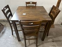 Full view of square bar height dining table with four chairs around it showing the overall set and condition.