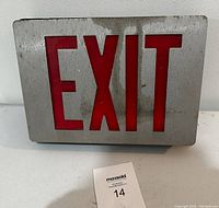 Front view of the rectangular metal exit sign with red letters spelling 'EXIT'. The metal shows some stains and surface rust, sign not installed.