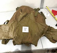 Top view of the tactical seat cover showing brown fabric, mesh and solid sections with adjustable straps and MOLLE webbing.