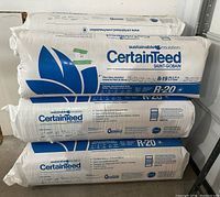 Stack of three white plastic-wrapped insulation bags showing CertainTeed branding and R-20 label