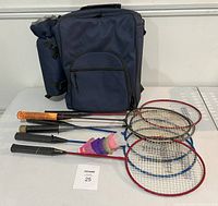 Nap sack picnic basket with four badminton rackets and shuttlecocks on white table