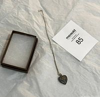 Full view of the sterling silver chain with heart pendant alongside a small box and lot number card.
