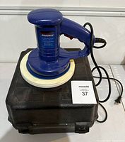 Simoniz 8-inch random orbit polisher/waxer sitting on top of its black plastic carry case with electric cord visible.