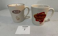 Front view of two Tim Hortons coffee mugs on a plain surface showing the logos